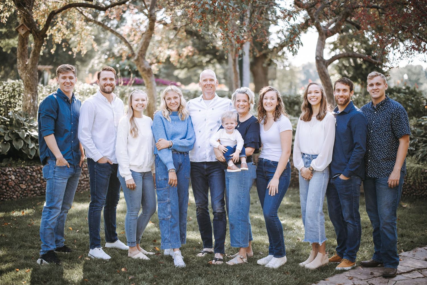 Large family group portrait outdoors wearing coordinated blue and white casual clothing.