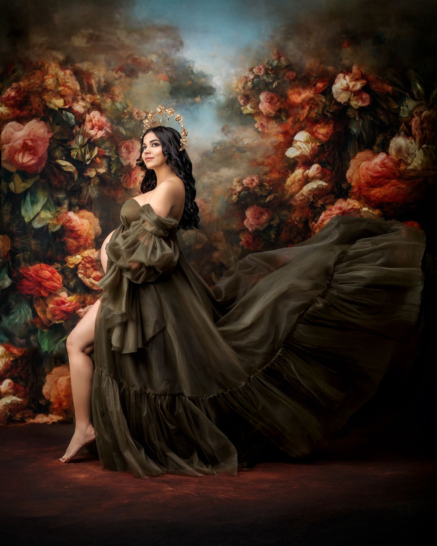 A pregnant mother stands looking radiant like a goddess against a dark moody floral backdrop in Sydney photoshoot studio.