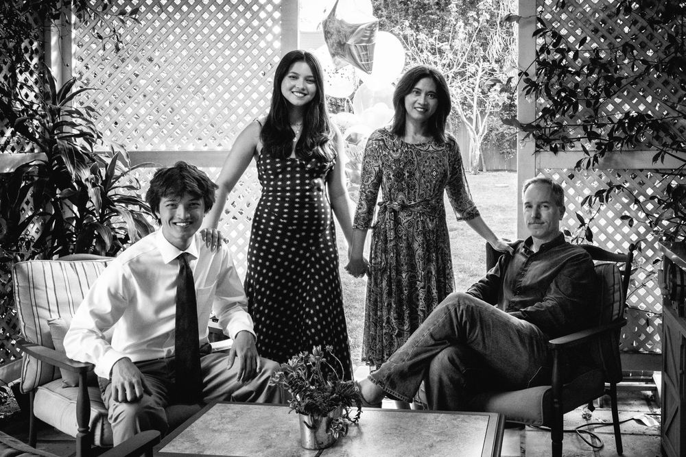 A black and white photograph of people relaxing in a vintage-style sitting area with lattice backdrop.