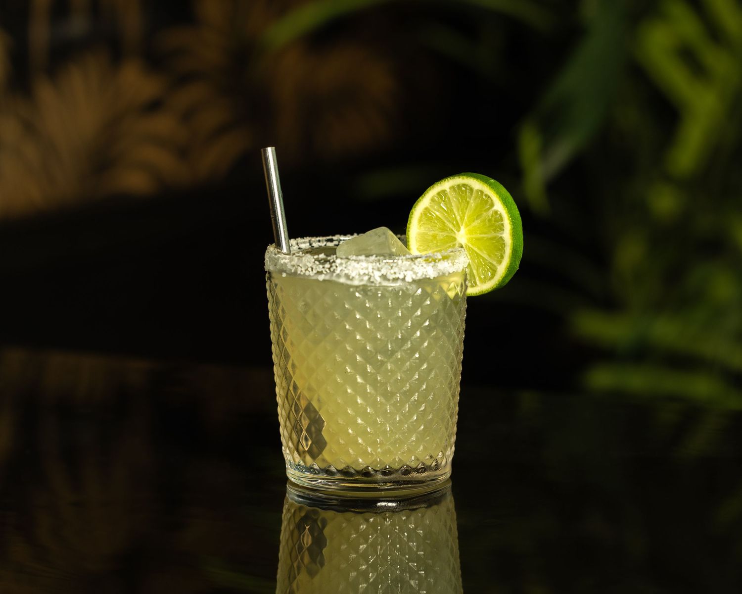 Row of elegant cocktails garnished with lime wedges served in textured glass tumblers.