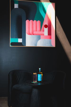 Modern geometric art installation with pink and teal shapes against a dark wall with minimal lighting.