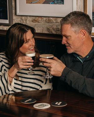 Cozy coffee date scene with drinks being shared across a dark wooden table.