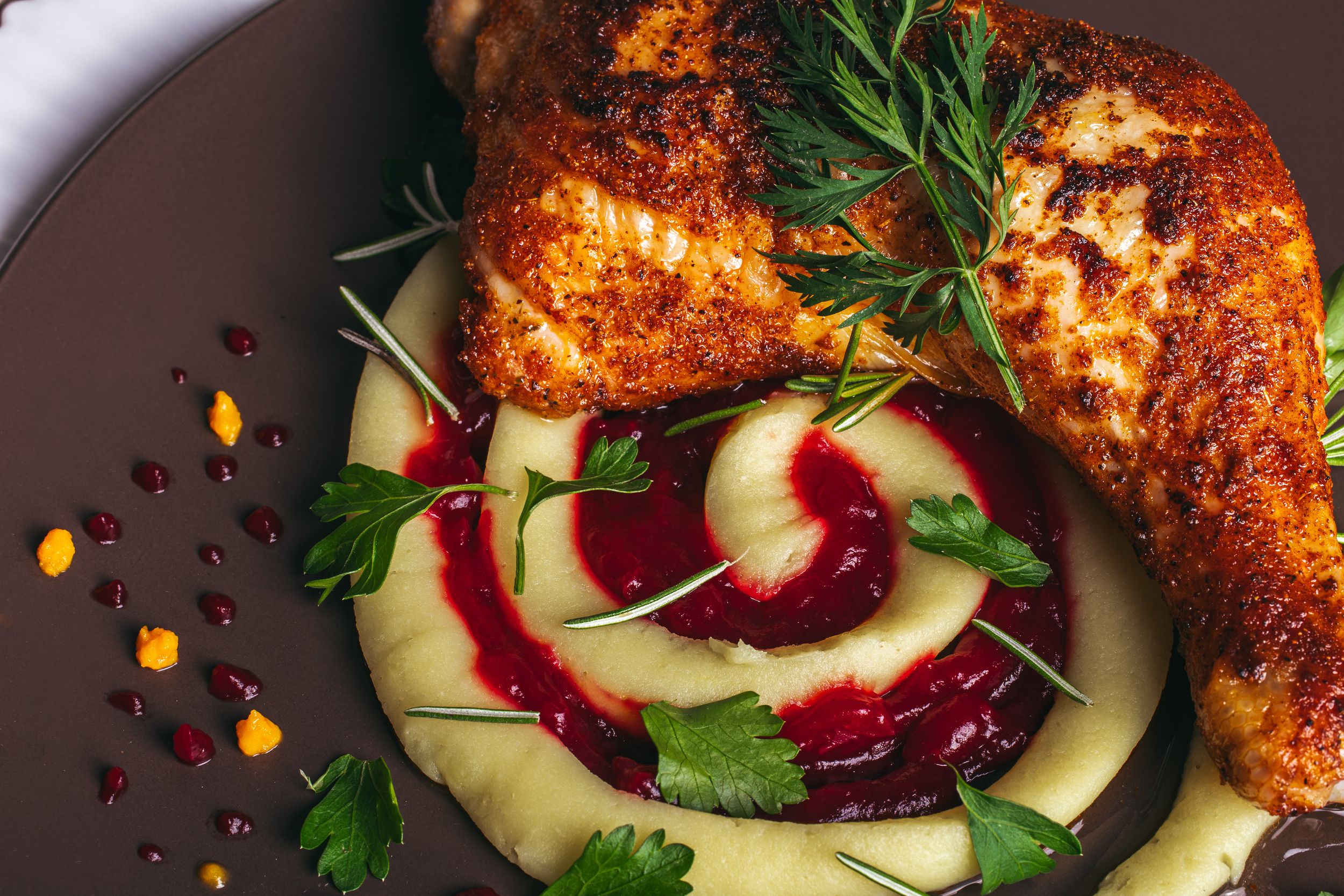 Grilled chicken breast served with circular arranged cucumber and beet salad garnished with herbs.