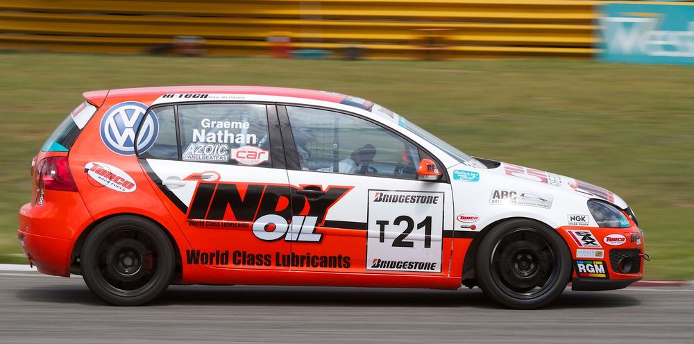 Red and black race-modified Volkswagen Golf racing on track with racing number 121.