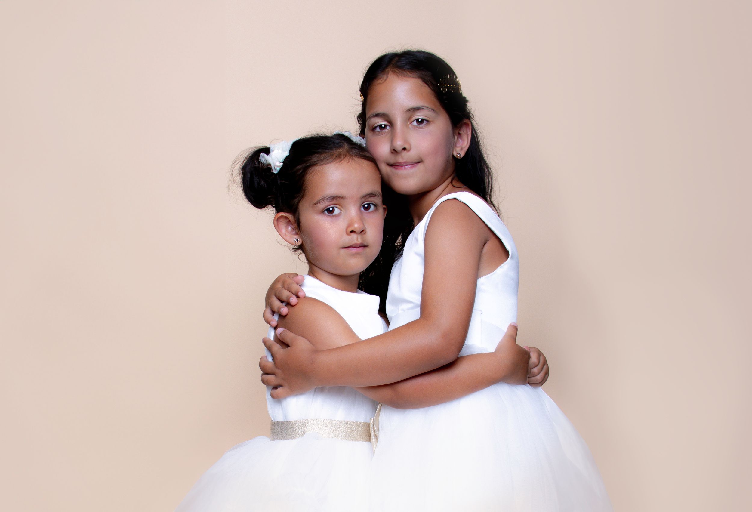 Two people embracing in a soft, minimalist studio setting against a beige background.