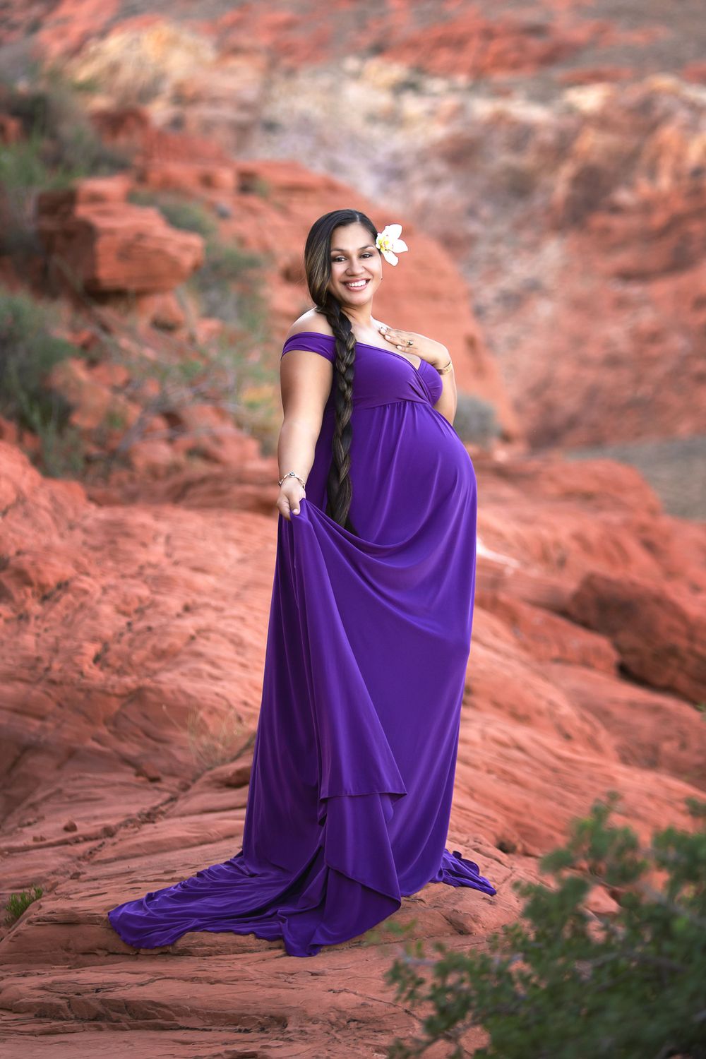 Dramatic maternity photos in a flowing purple gown on red rock formations.