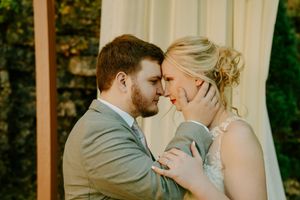 Tender moment between newlyweds during outdoor autumn wedding ceremony.