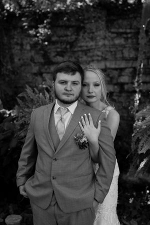 Black and white romantic wedding portraits against stone wall backdrop.
