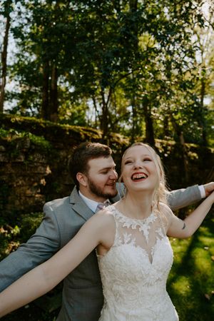 Joyful wedding portraits captured in natural outdoor setting with stone wall backdrop.