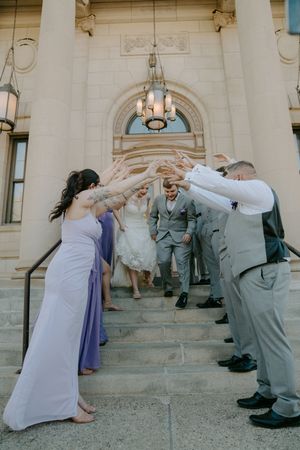 Fun wedding party photos showing playful poses on stone steps of an elegant building.