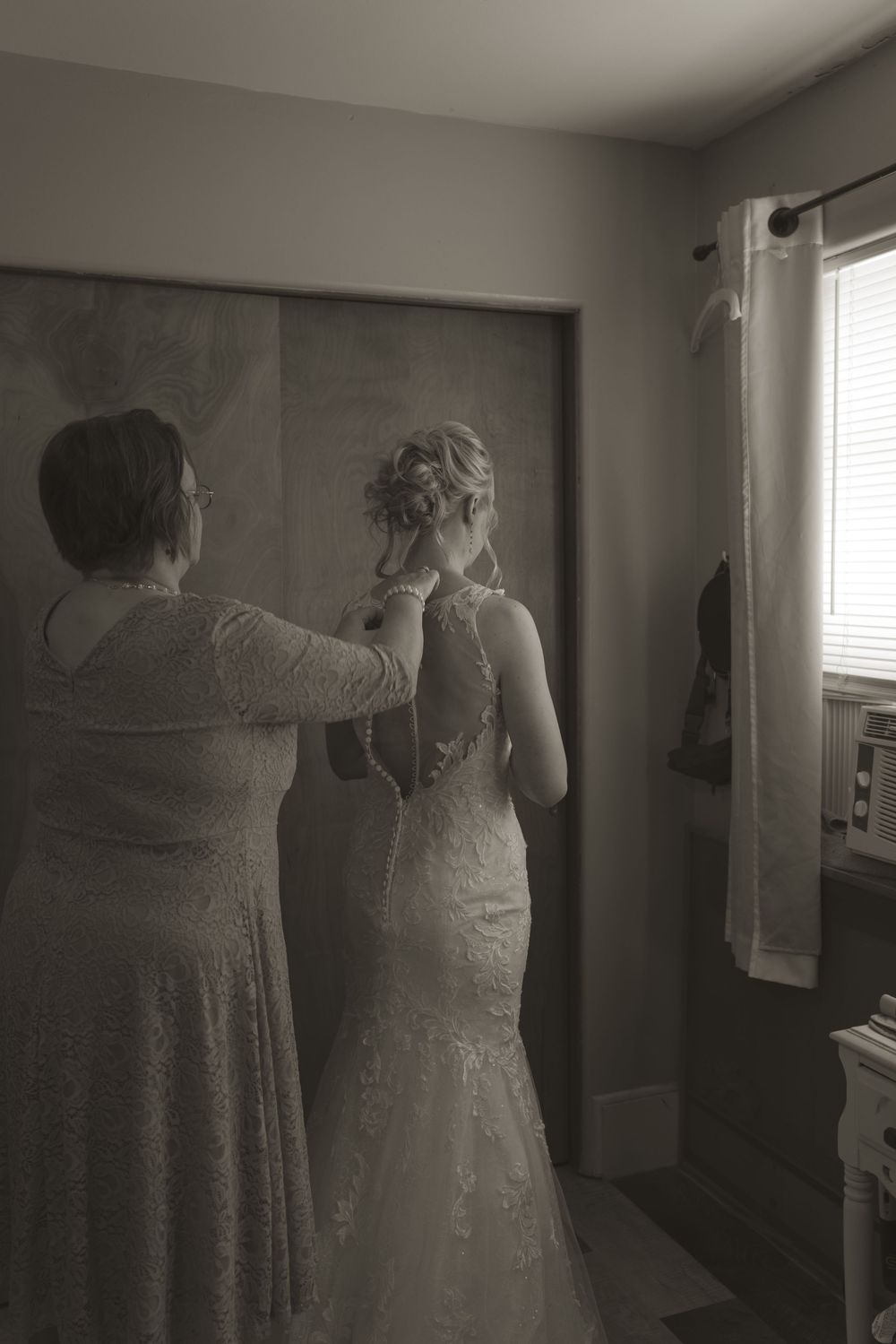 Black and white getting ready scene with wedding dress preparations.