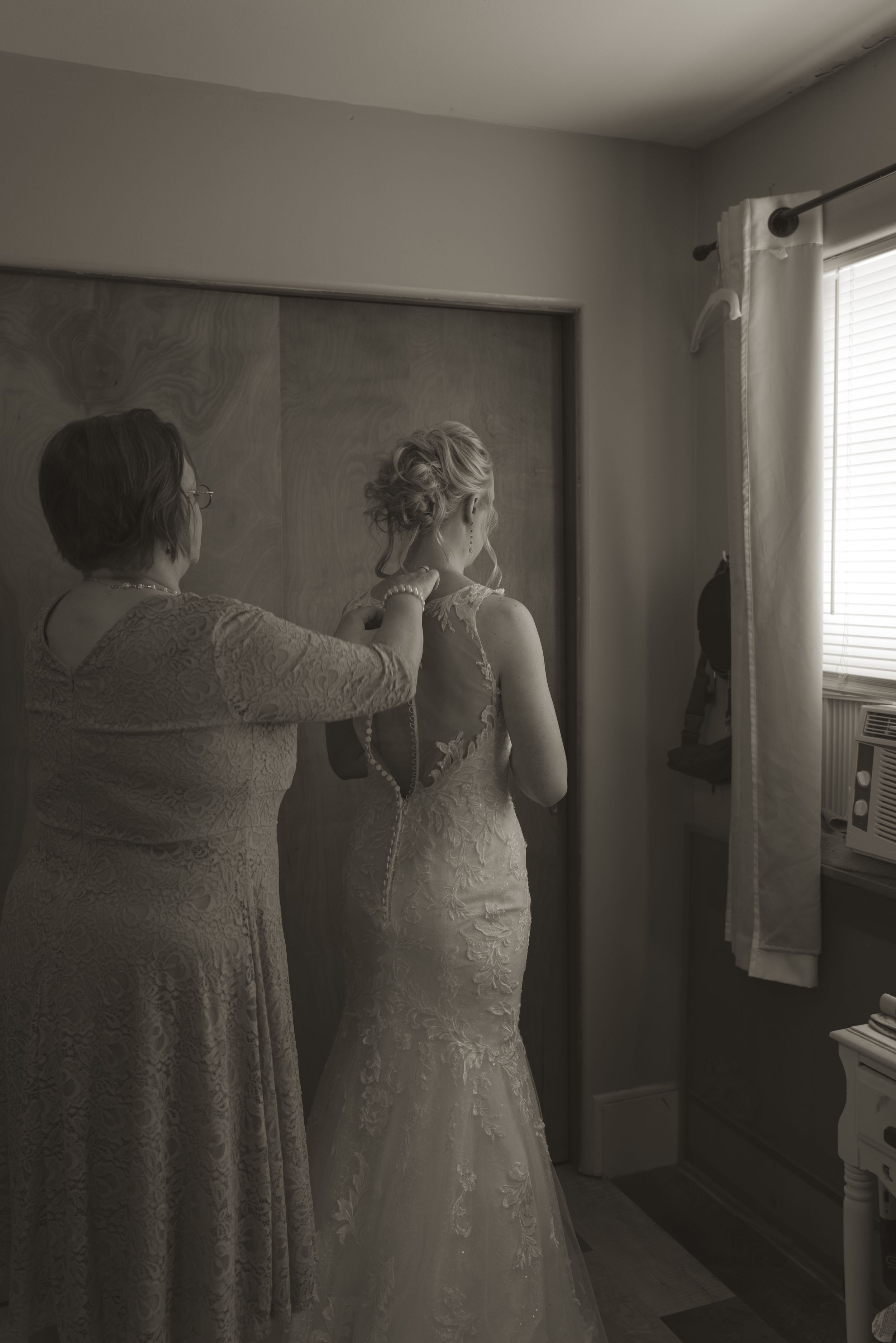 Black and white getting ready scene with wedding dress preparations.