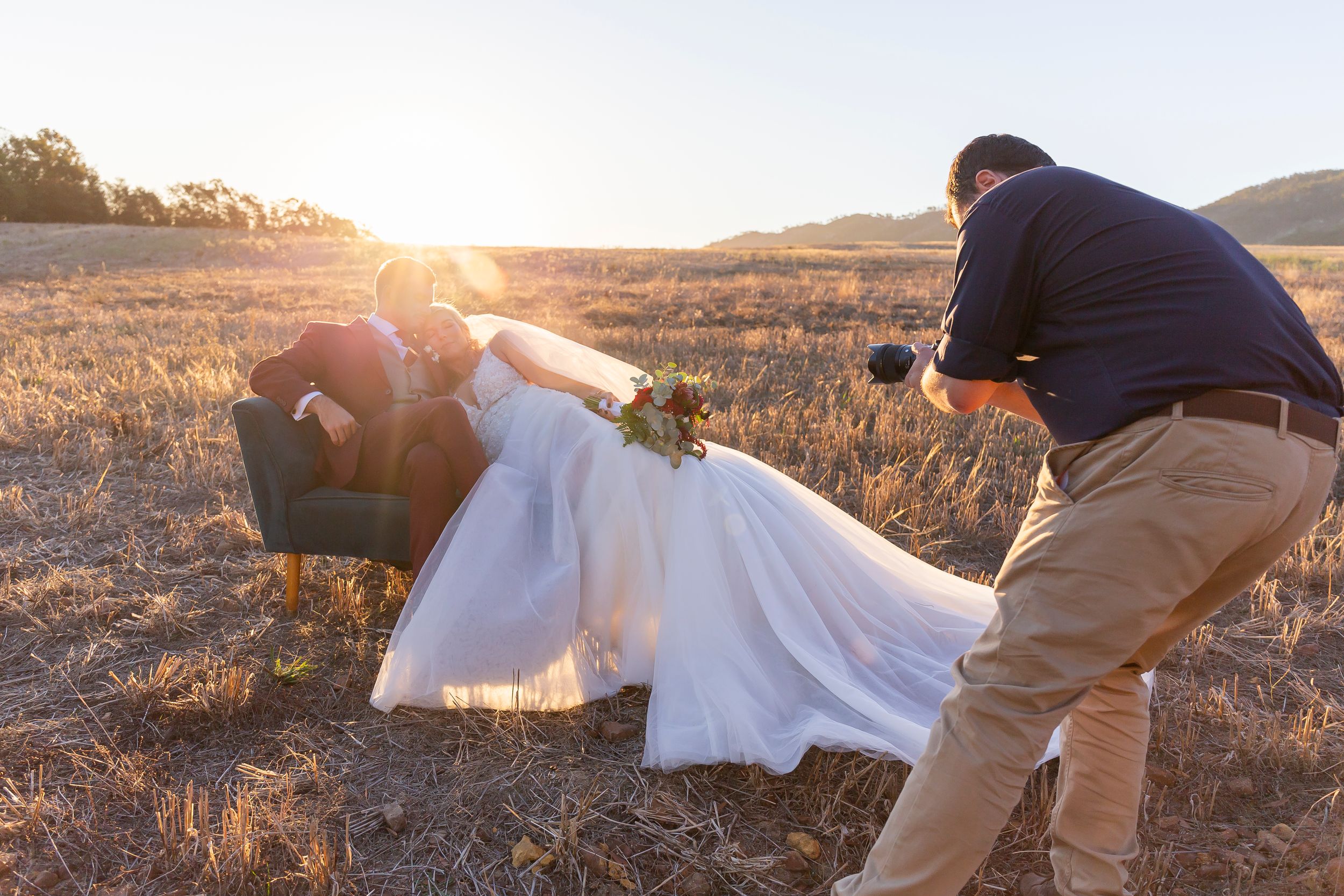 Couple poses dramatically in golden sunset light on a hillside.