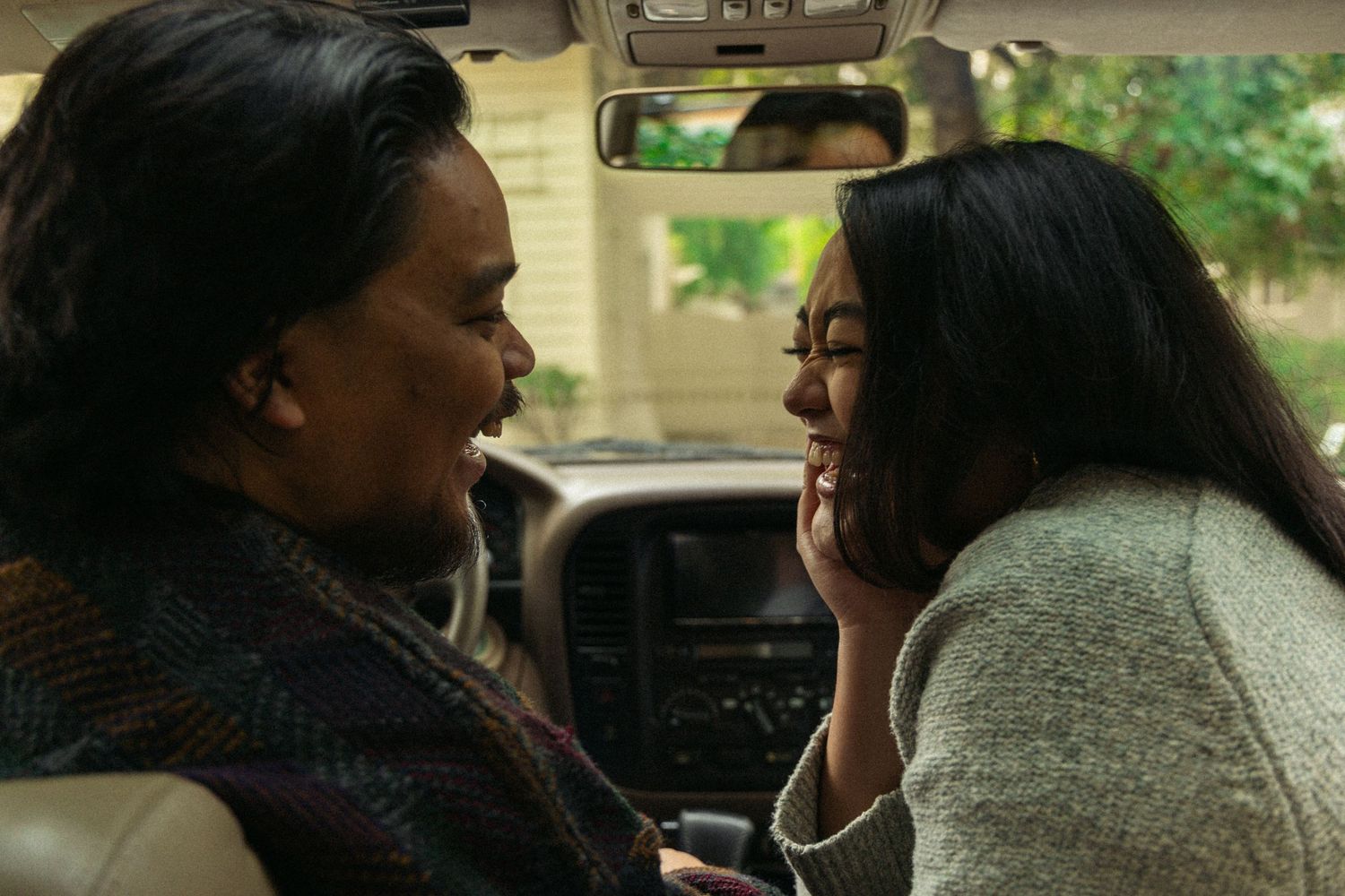 Two people share a joyful moment while sitting in a car together.