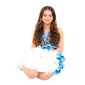A cheerleader in a blue and white uniform kneels while holding white and blue pom poms.