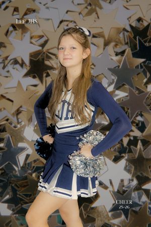 Cheerleader in navy and white uniform poses against abstract background with silver metallic confetti pattern.