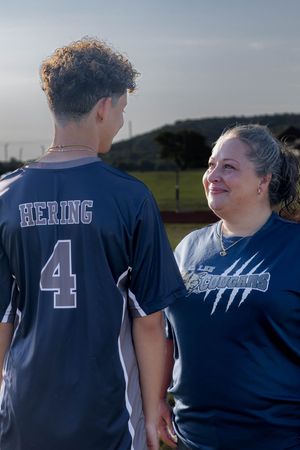 Two people in dark blue shirts outdoors, one wearing a jersey with number 4 and "HERING" on the back.