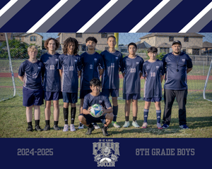 A youth soccer team poses in navy blue uniforms on a sports field for their team photo.