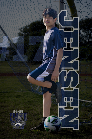 Youth soccer player in navy uniform poses with ball against goal net for sports team photo.