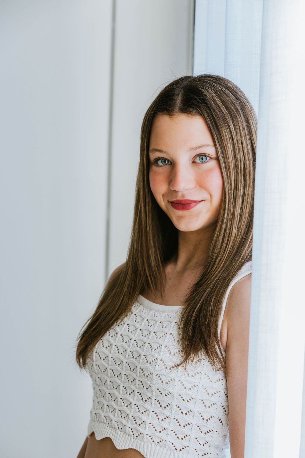 Portrait series of someone wearing a sleeveless white lace top against a light background showing different facial expressions.