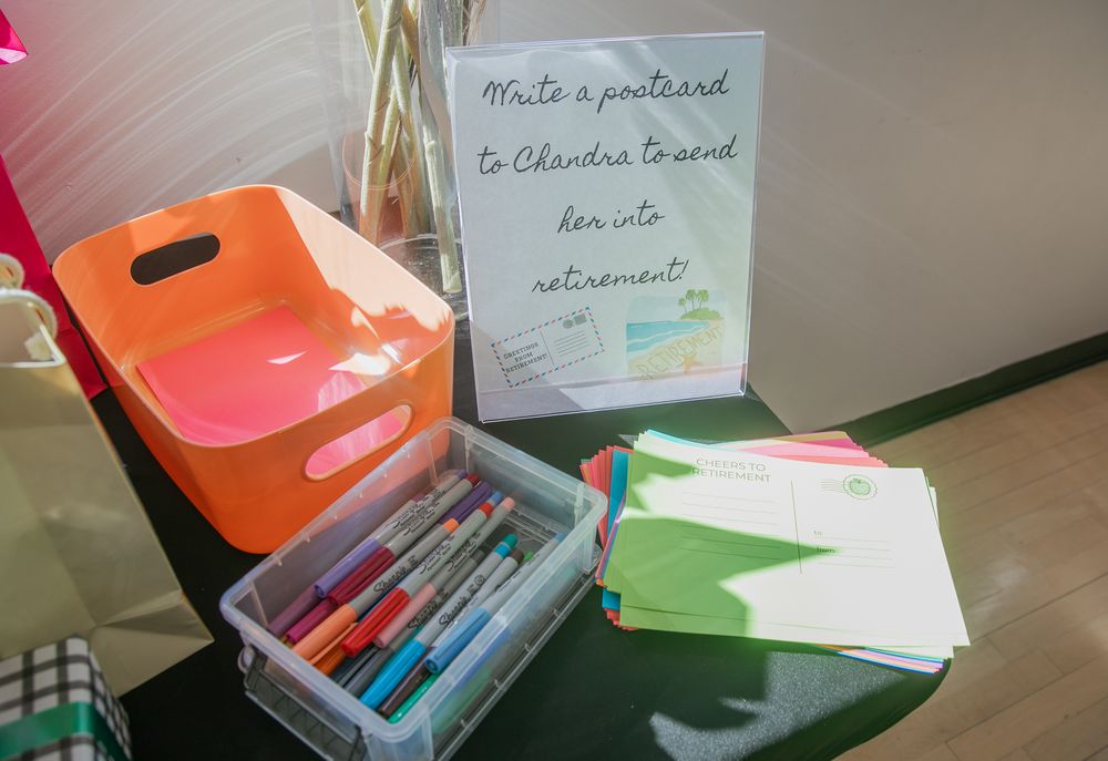 Office supplies and storage containers arranged on a desk with a framed note and colorful markers.