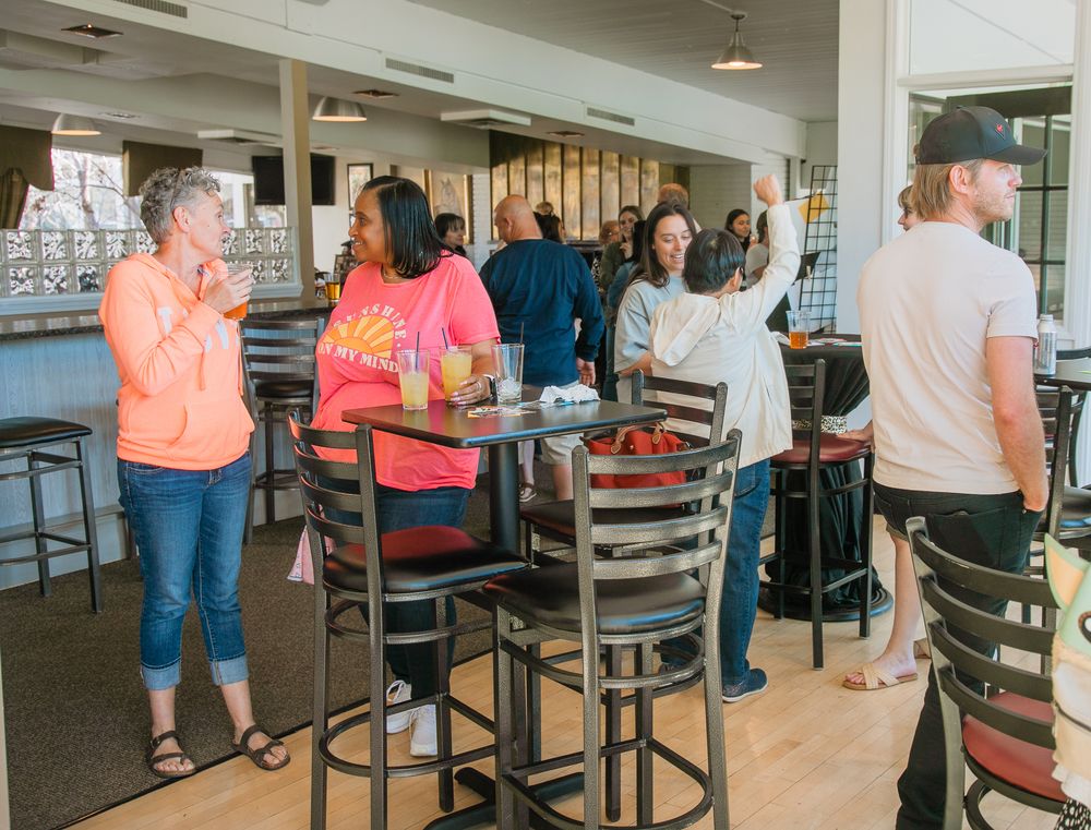 People gathered at a casual dining establishment with high tables and chairs in a bright, open space.