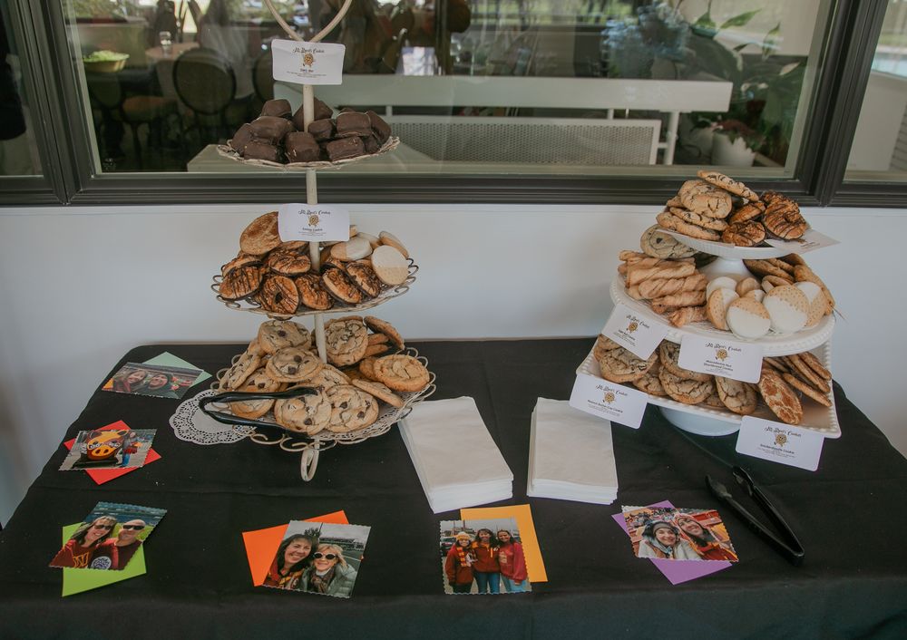Multiple platters of baked goods displayed on a table with photos and merchandise laid out below.