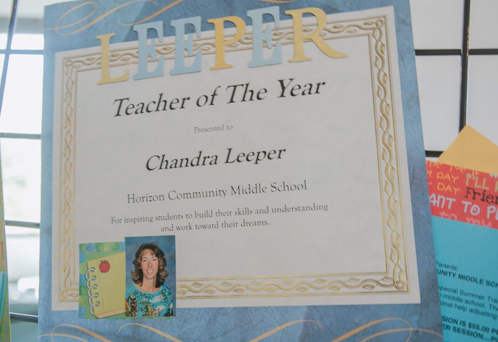 A Teacher of the Year certificate award displayed in an ornate gold border frame with decorative details.