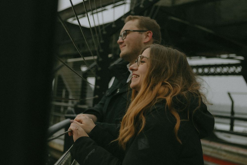 A couple shares a happy moment together on what appears to be a train platform on an overcast day.