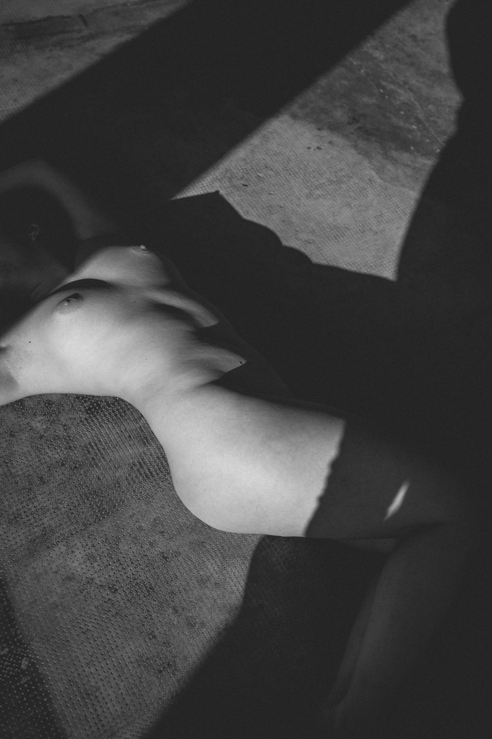 Black and white artistic photograph showing abstract shadows and light patterns on textured fabric surface.