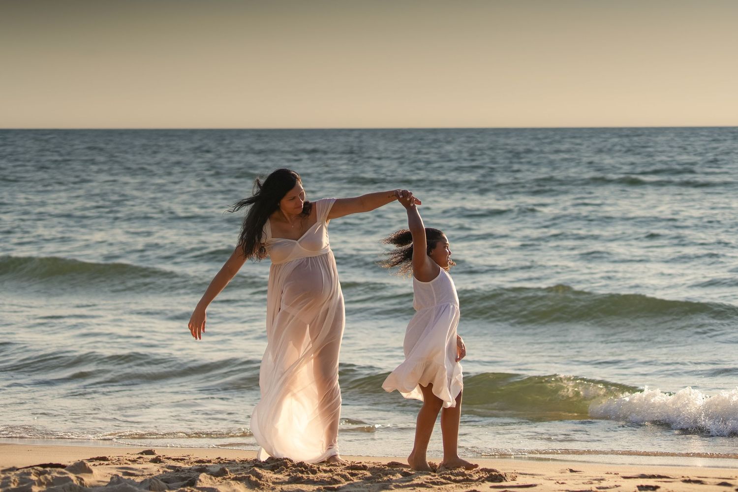 Mother and daughter playing together along the Lake Michigan shoreline during a sunset family session