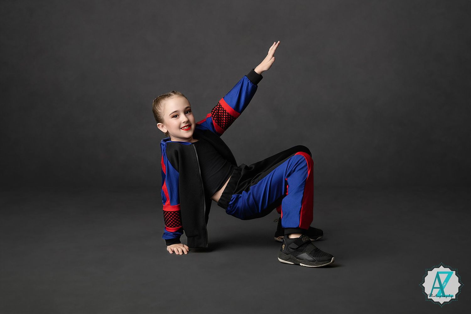 Dancer in blue and black athletic wear strike a dynamic pose against dark background during performance routine.