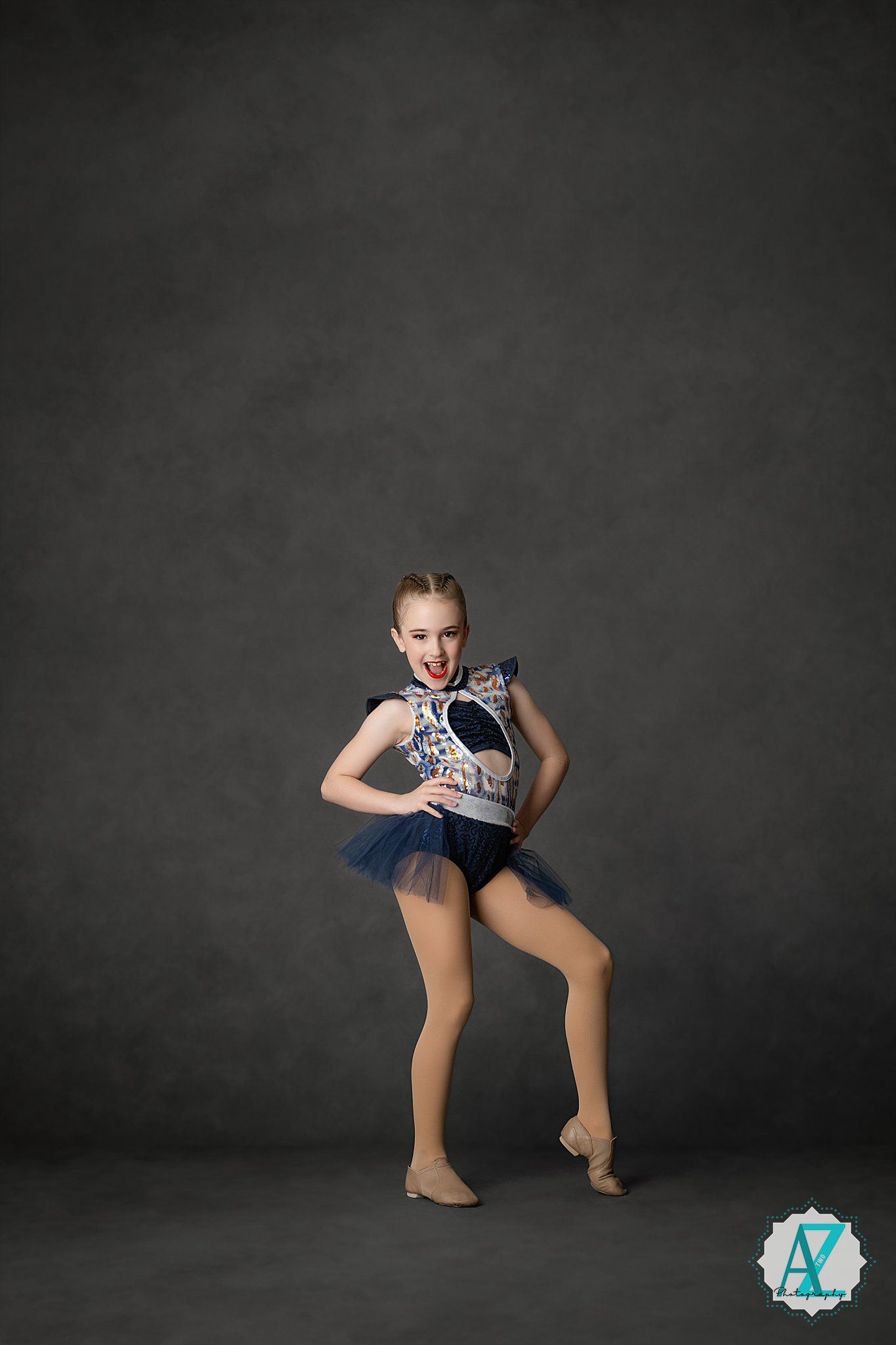 Dancer in blue costume performs dynamic dance moves in studio setting.