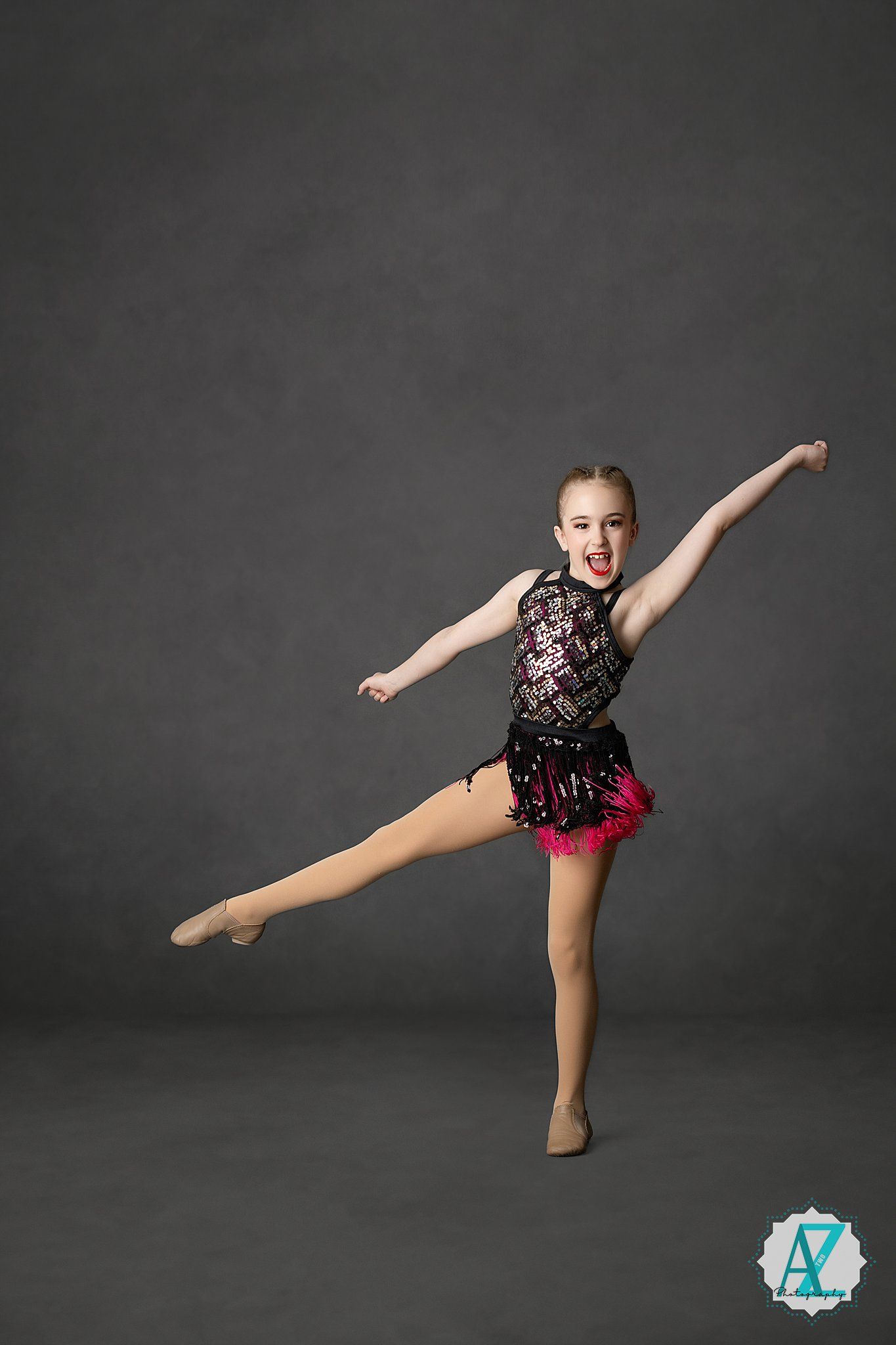 Dancer performs elegant pose in black lace and pink costume against dark background.