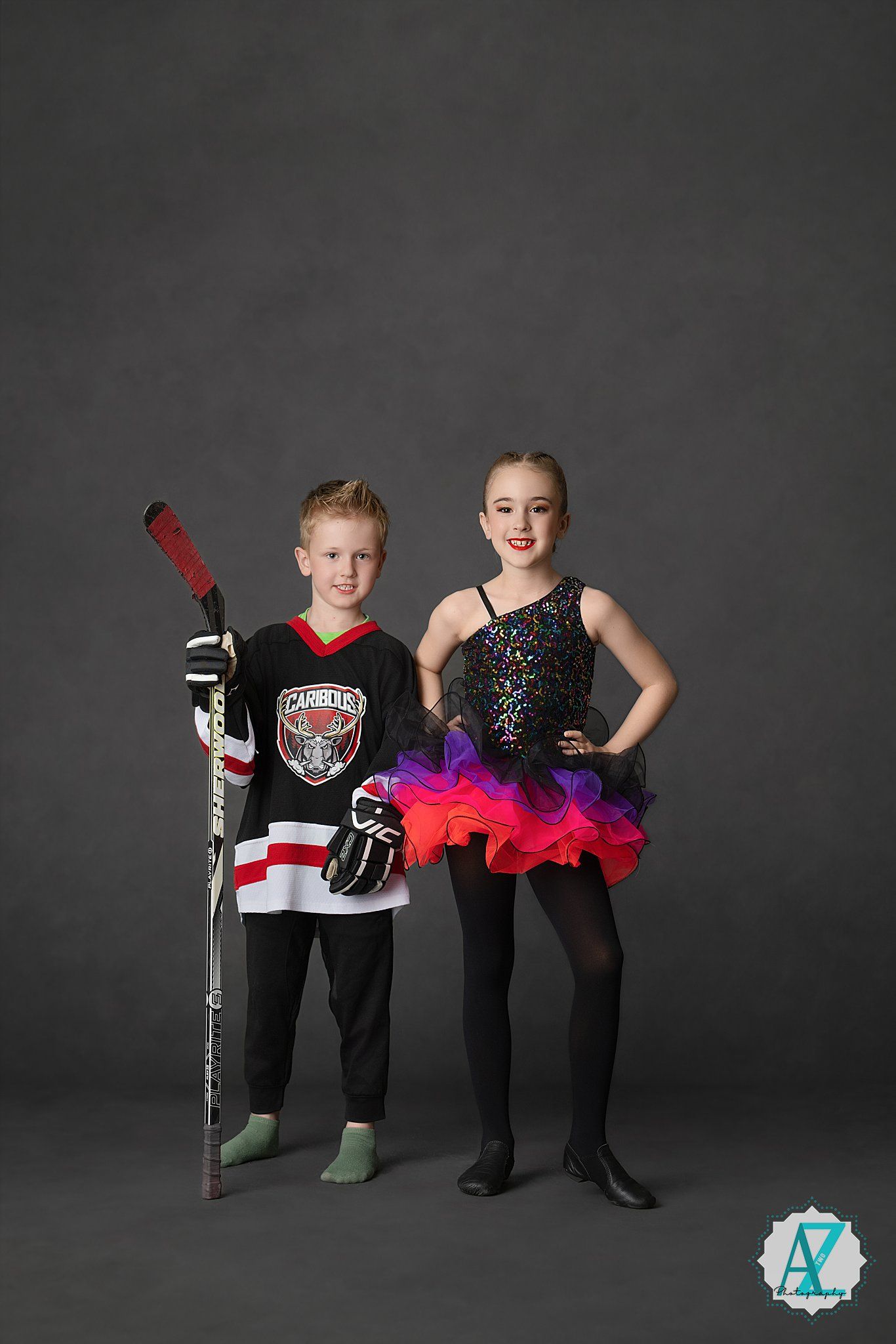 Hockey player and dancer pose together in contrasting athletic and performance outfits against grey backdrop.