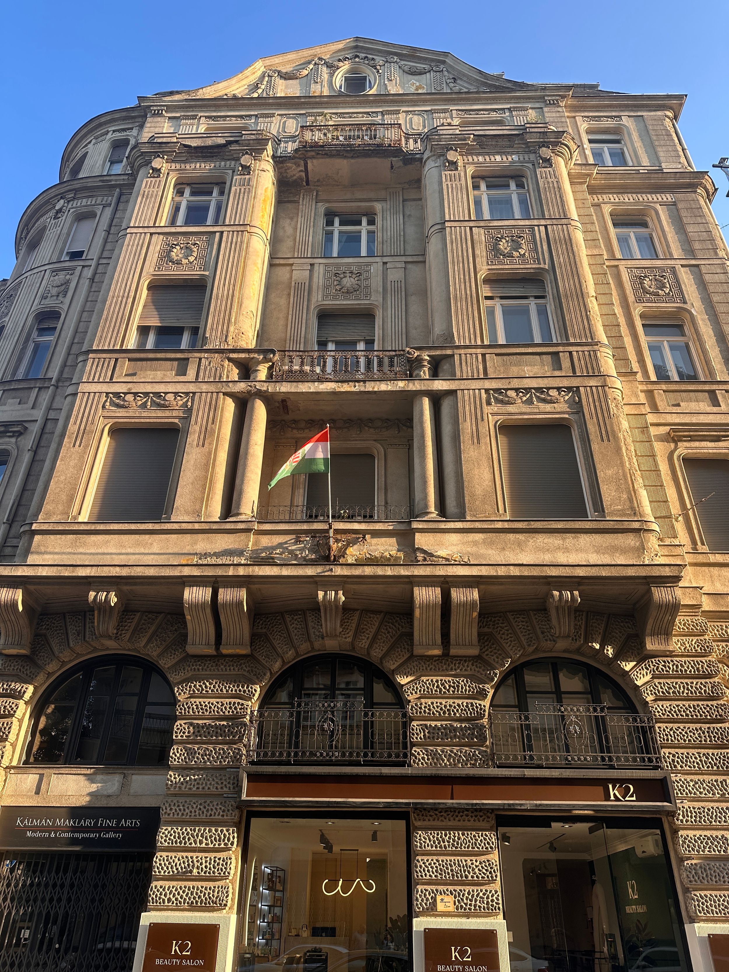 Ornate Beaux-Arts style building facade in Vienna with classical architectural details and balconies illuminated by golden sunlight.
