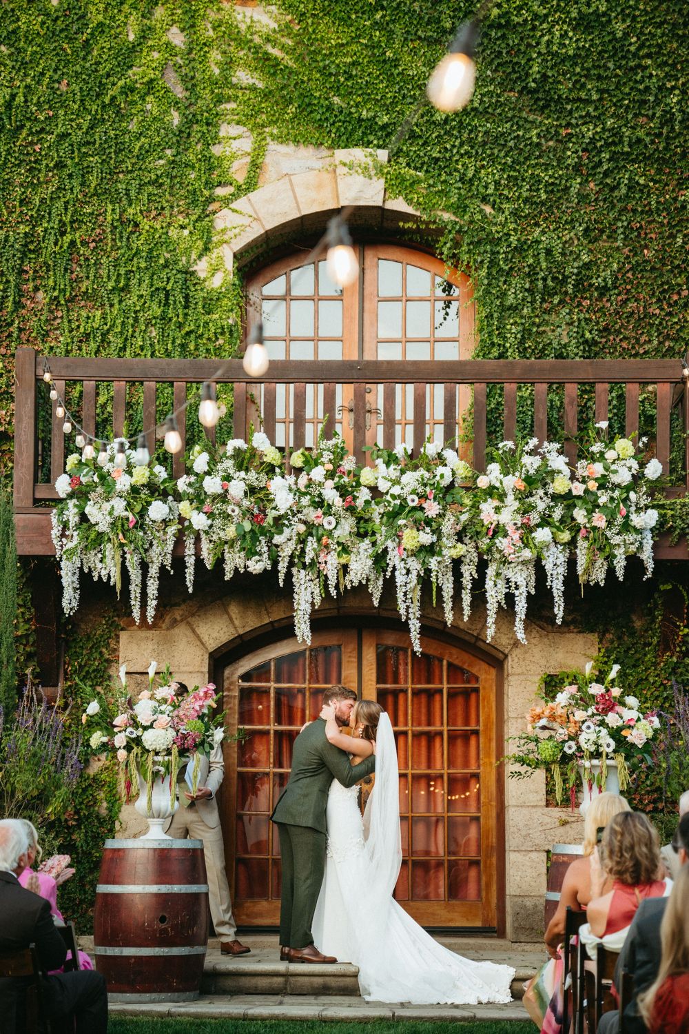 A series of wedding photos showing an ivy-covered stone building with white floral decorations and wine barrels.