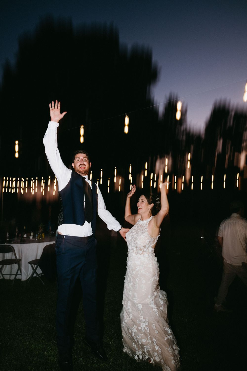 Dancing couple celebrates joyfully at a nighttime wedding reception with raised arms in wine country, Sonoma County, CA