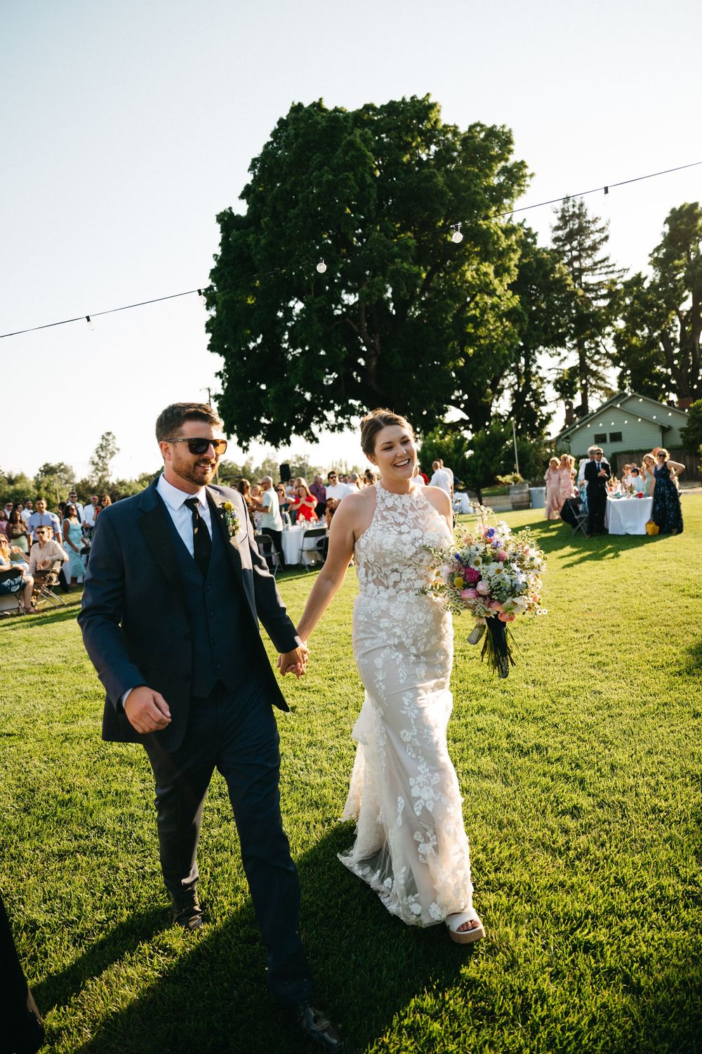 Wedding party dancing and celebrating on a green lawn during sunset at an outdoor reception  in Healdsburg, CA