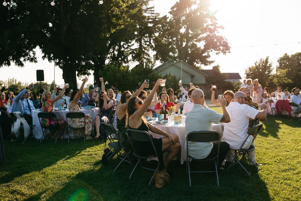 Golden sunset illuminates an outdoor wedding reception on a grassy hillside with tables set up for dining  in Healdsburg, CA