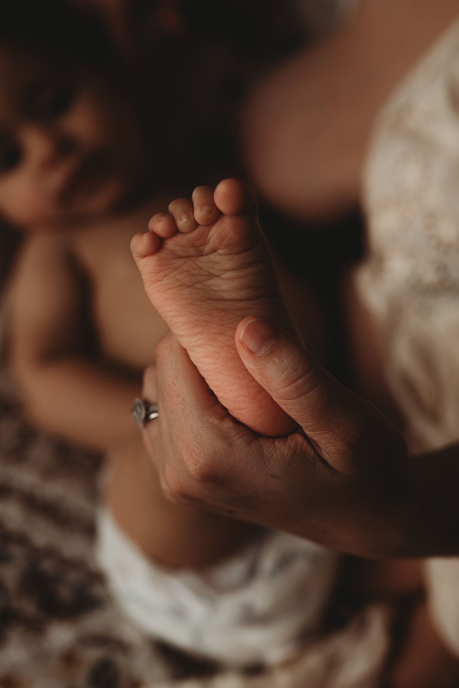 Close-up view of tiny baby feet and hands resting on soft textured fabric.