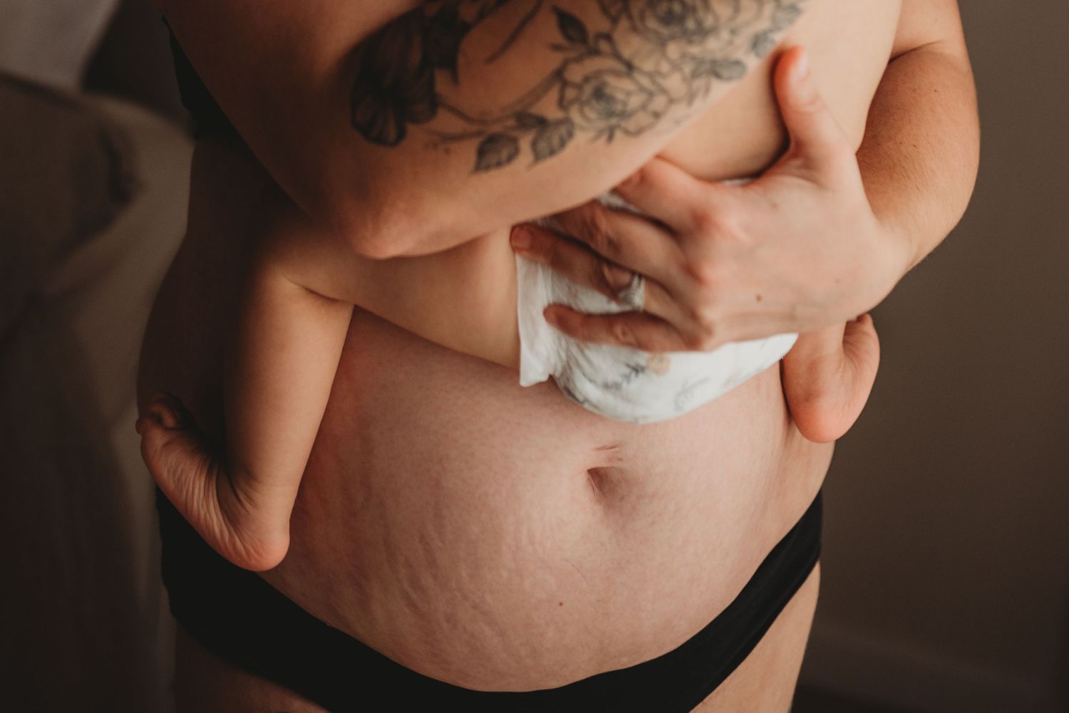 Close-up detail of stretch marks and tattoos in intimate boudoir style.