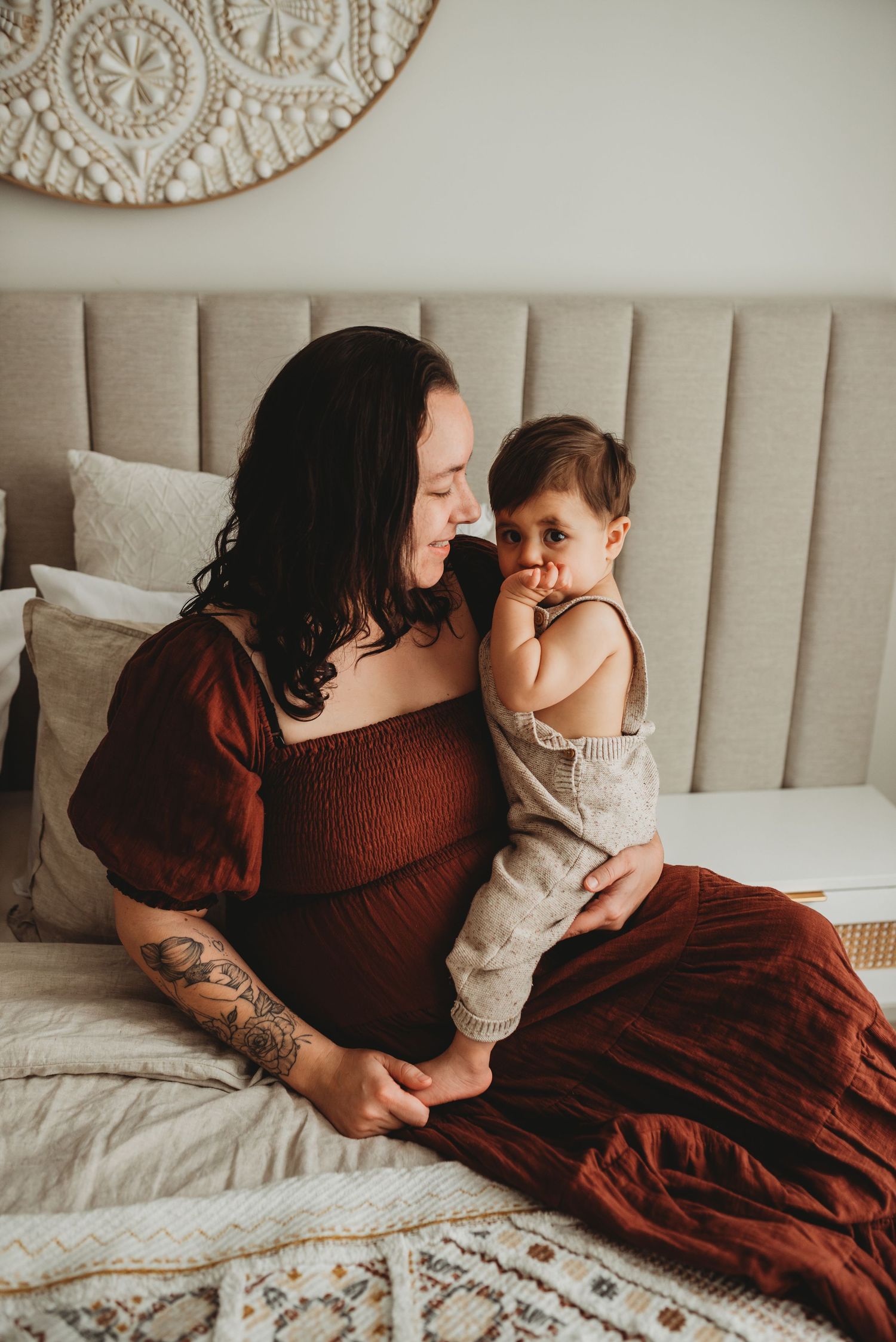 Tender moment between parent and child on a beige upholstered headboard bed.
