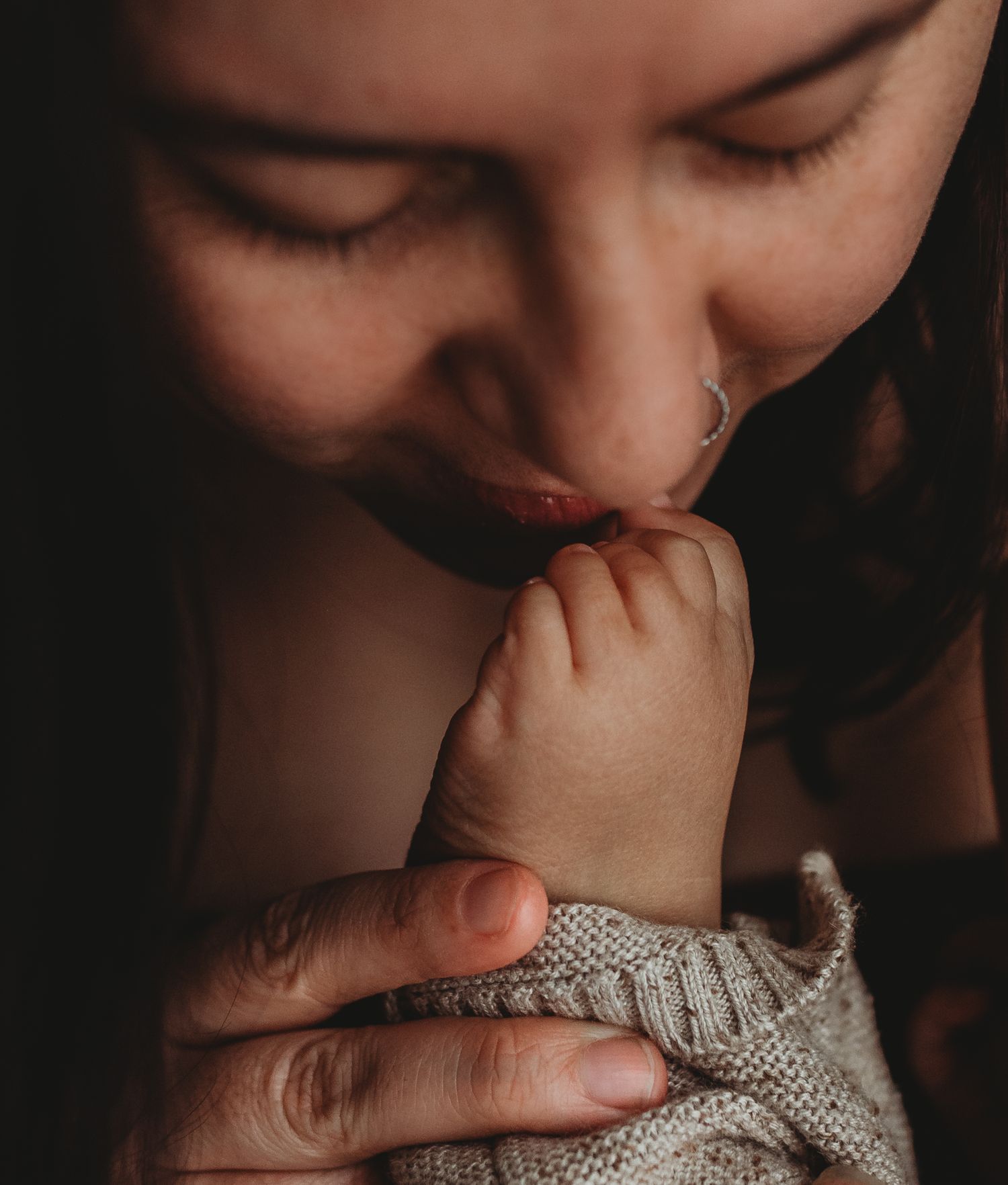 Intimate close-up of gentle nurturing moment in moody lighting.