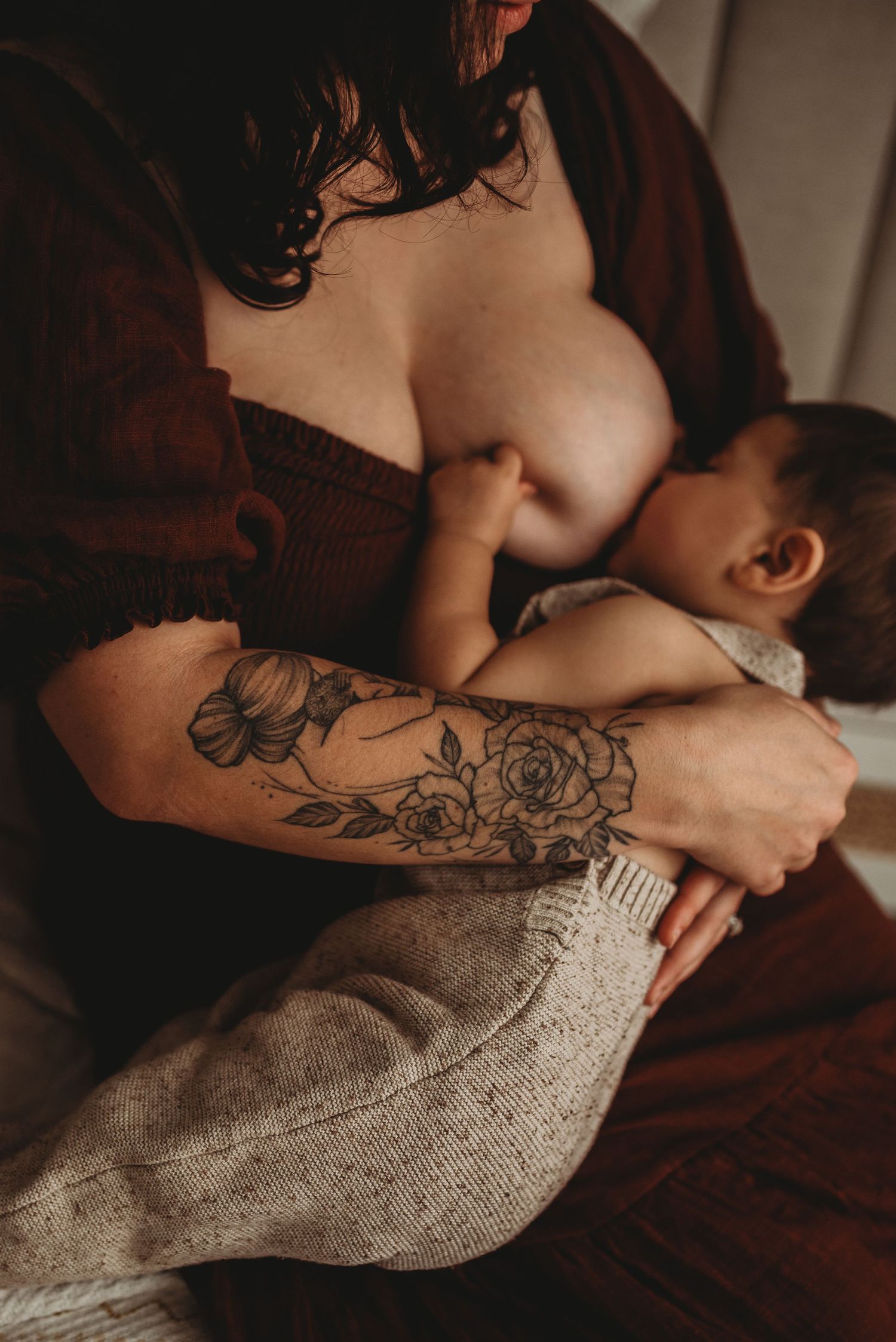 Intimate close-up of a tattooed person holding a gray knit blanket in moody lighting.
