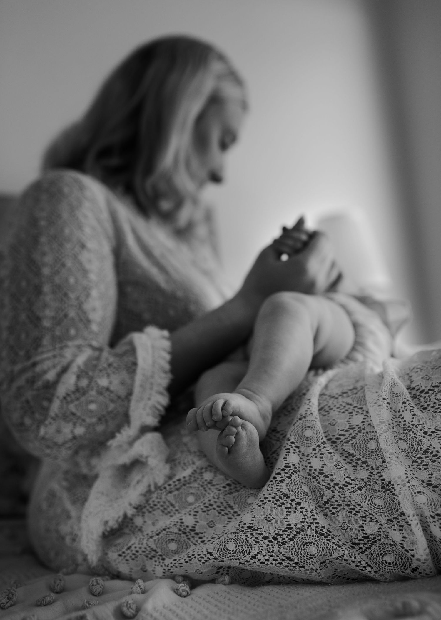 Black and white portrait on lace fabric with soft, dreamy lighting.