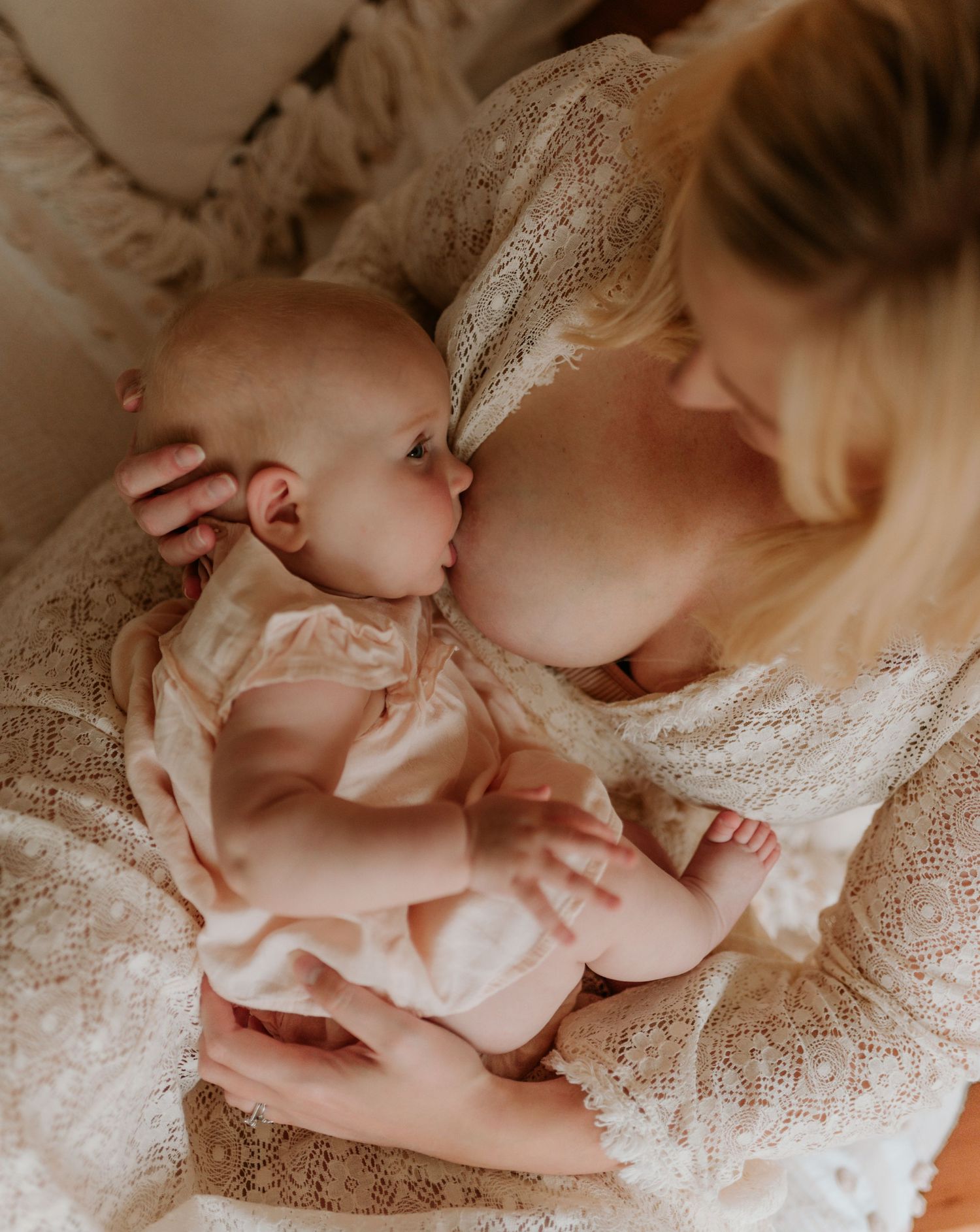 Tender maternal moment photographed with delicate lace details in natural light.