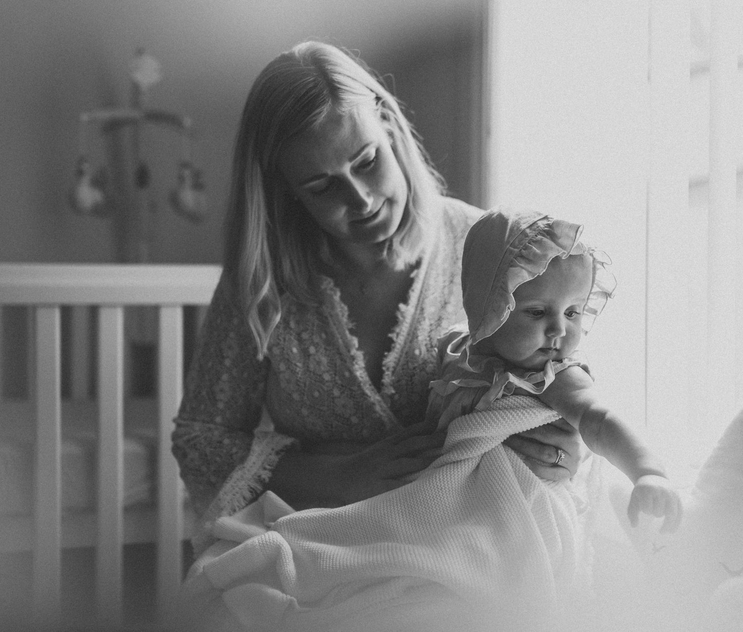 Black and white intimate portrait by window light in nursery setting.