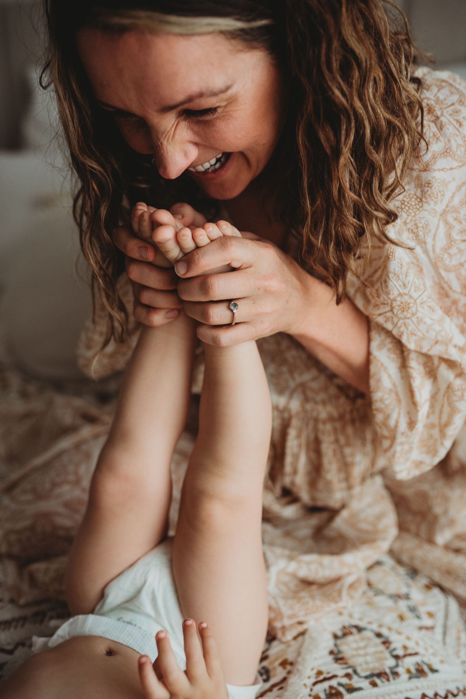 Person in lace dress sitting on textured bedding in natural light.