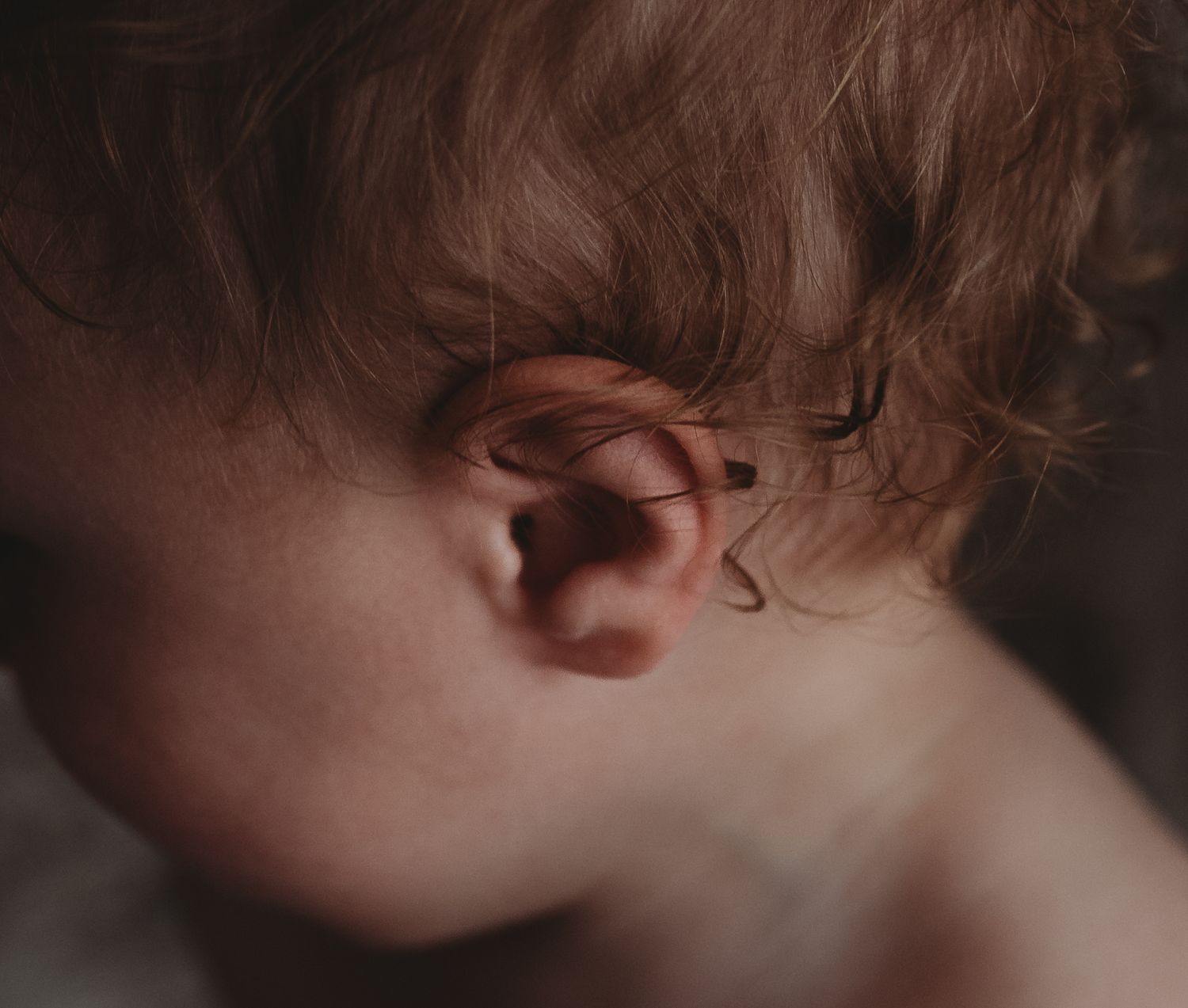 Intimate lifestyle photography captures tender moments between parent and child on a bed with soft lighting.